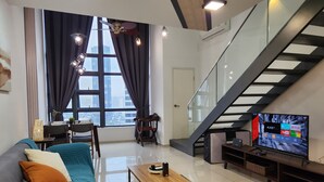 Una sala de estar moderna con un ventanal grande, una escalera y un televisor de pantalla plana.