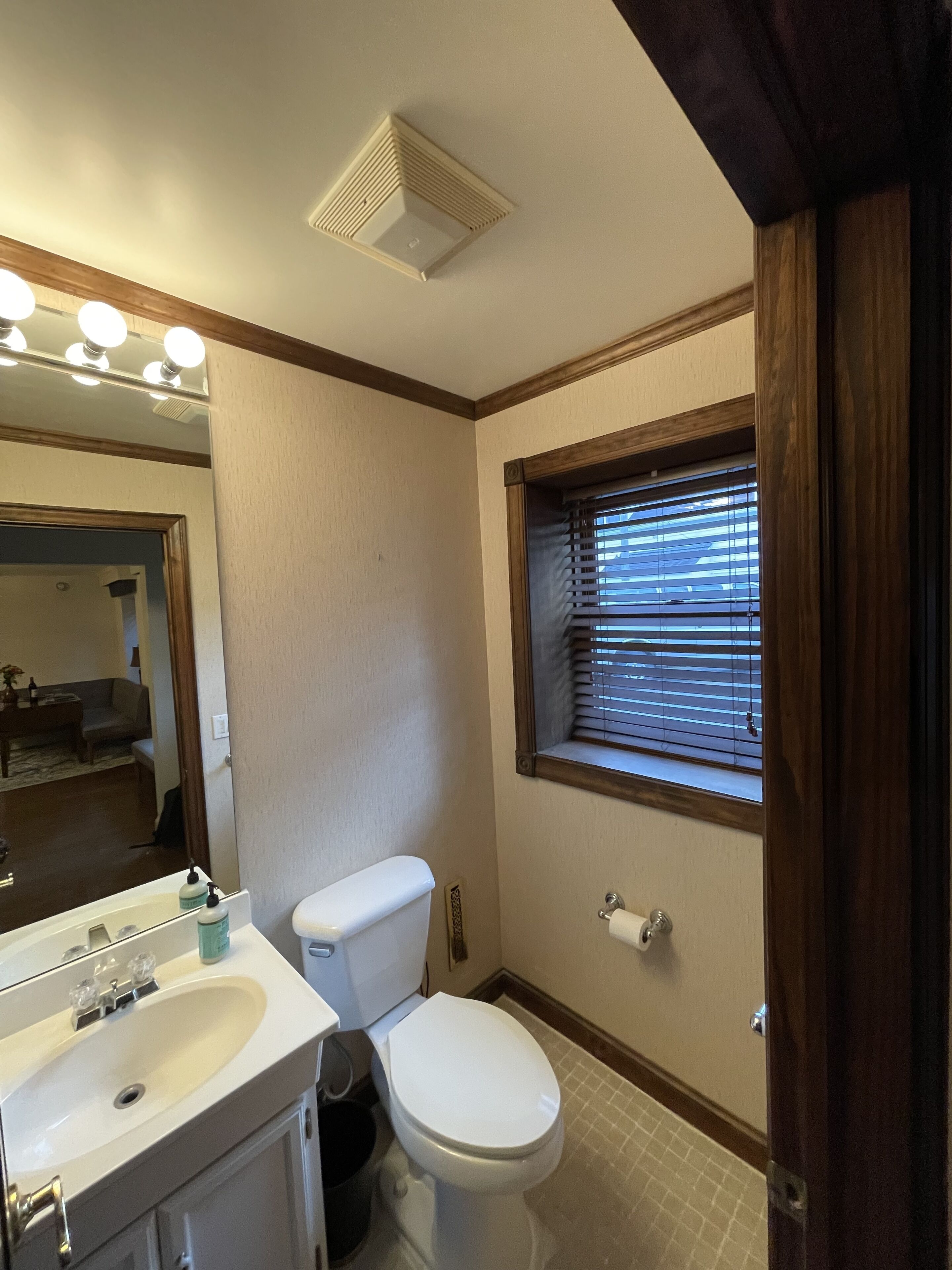 A bathroom with a toilet, sink, and window with blinds.