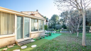 Una casa amb un gran finestral de vidre, un prat verd i un arbre.