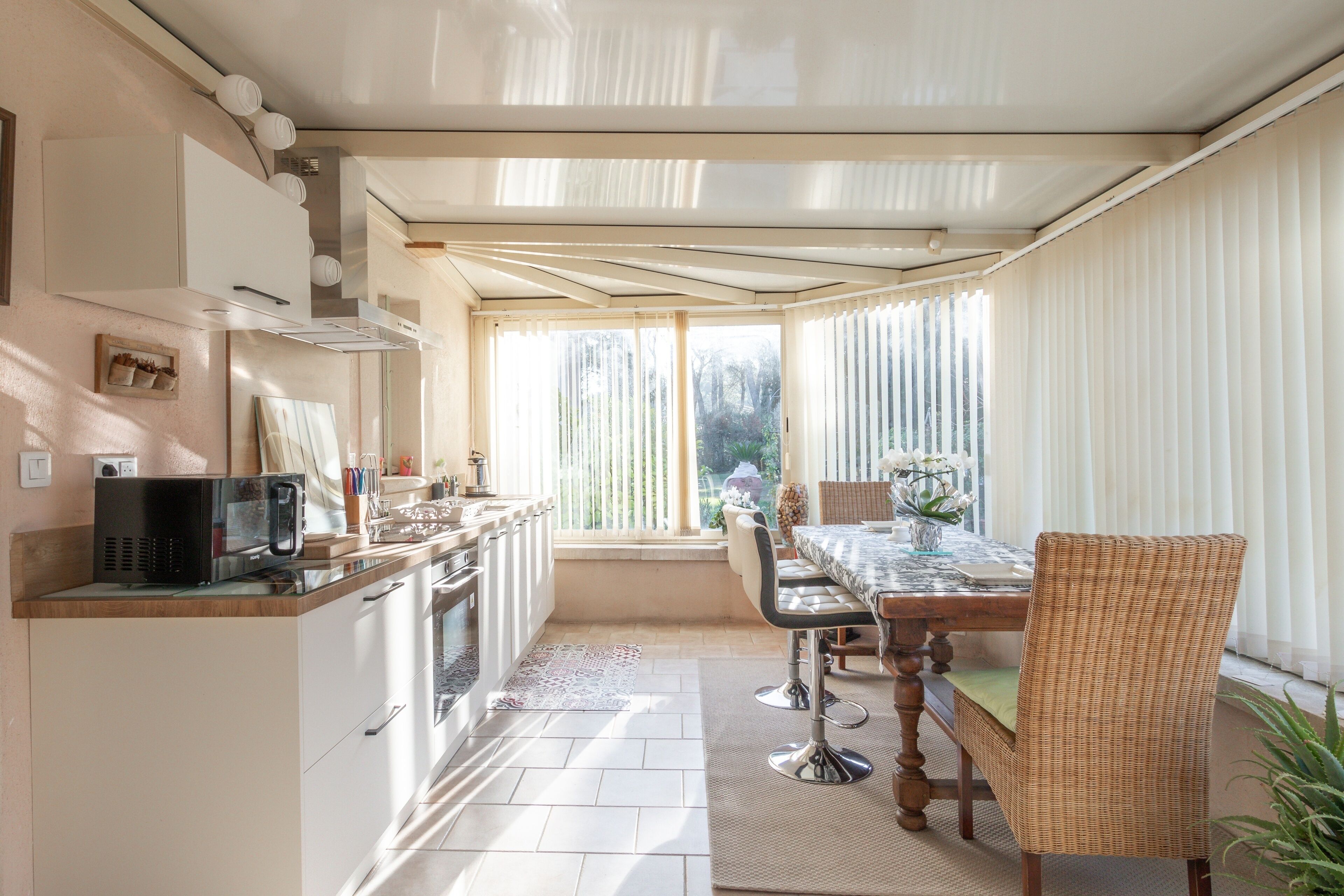 A modern kitchen with white cabinets, a microwave, and a dining area with a table and chairs.
