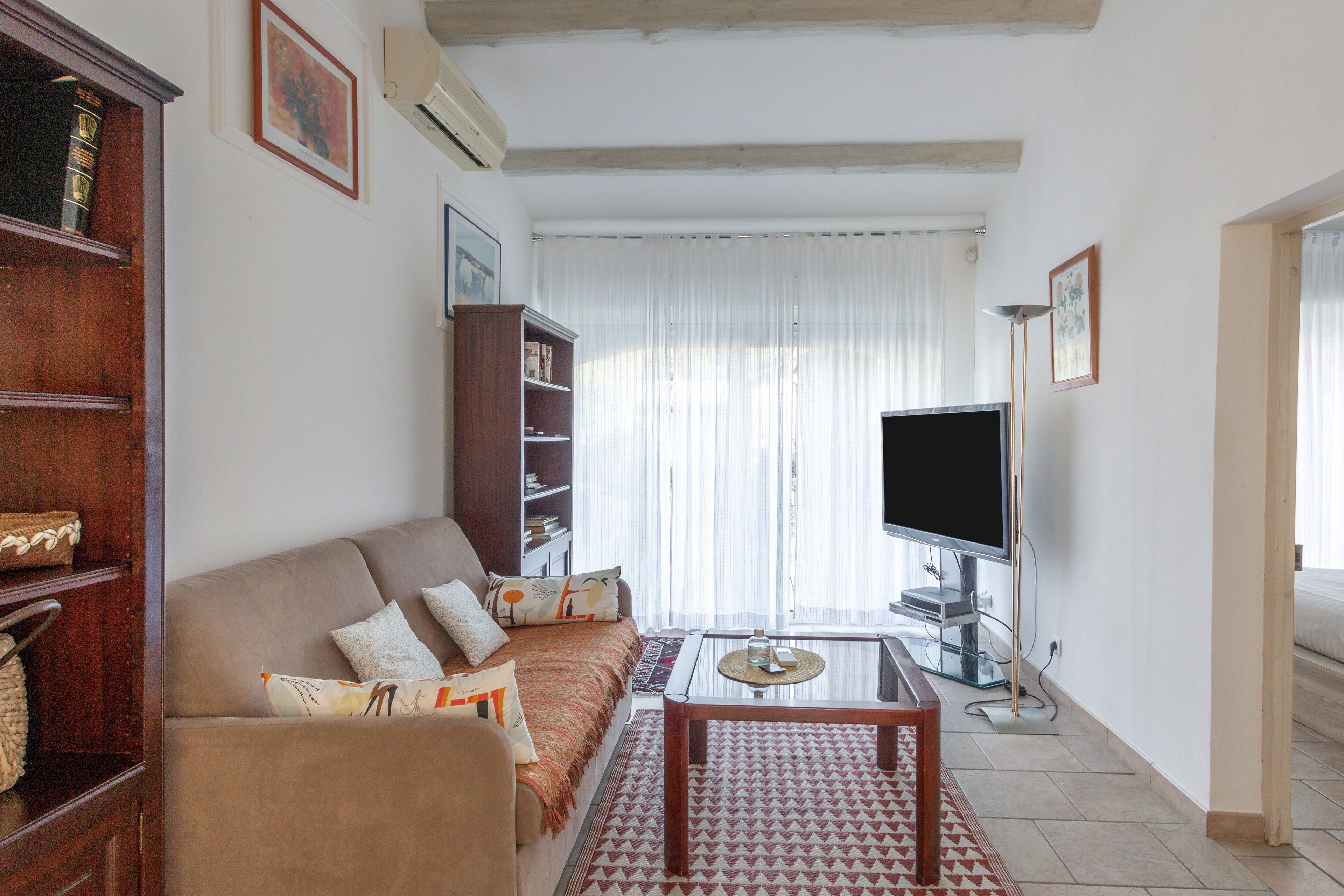 A living room with a sofa, coffee table, TV, and bookshelf.