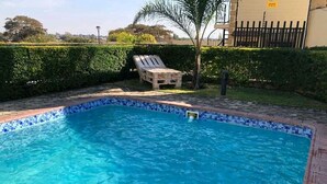 Ein Schwimmbecken mit einer gefliesten Kante, umgeben von einer Ziegelmauer und einer Holzterrasse.