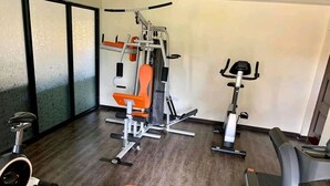 Ein Fitnessstudio mit Trainingsgeräten, darunter ein Laufband, ein Ergometer und Kraftgeräte.