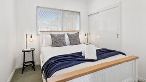 Une chambre à coucher avec un lit, des lampes de chevet, une fenêtre et une porte.