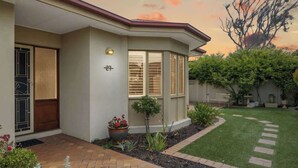 Une maison d’habitation avec une allée pavée, un petit jardin agrémenté de plantes en pot et une pelouse bien entretenue.
