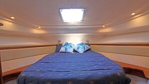 Una habitación compacta y bien iluminada con una cama individual, un tragaluz y un ventanal pequeño.