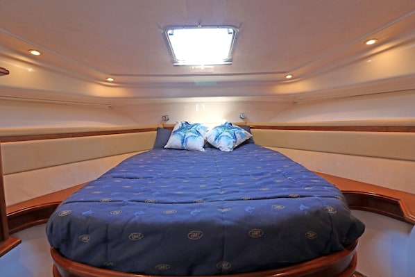 Una habitación compacta y bien iluminada con una cama individual, un tragaluz y un ventanal pequeño.