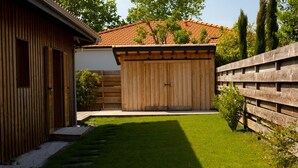 Ein Holzhaus mit einem umzäunten Garten, einem kleinen Schuppen und einem gepflegten Rasen.