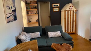 Ein gemütliches Wohnzimmer mit einem grünen Sofa, einer Holzkommode und einem Bücherregal.