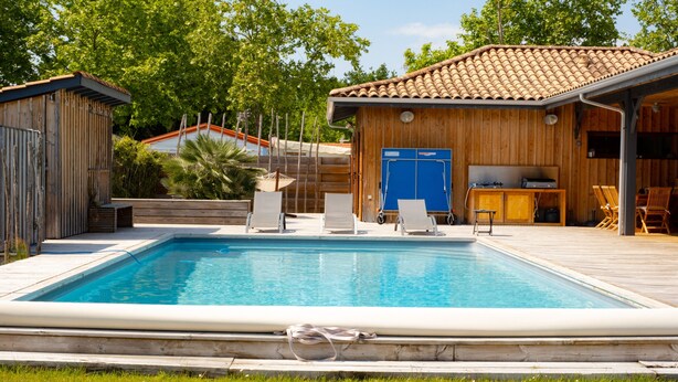 Ein rechteckiger Pool mit Liegestühlen und einer Holzterrasse.