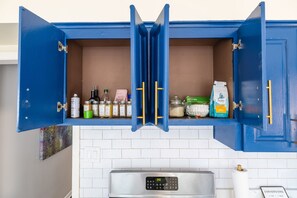A kitchen with a blue cabinet containing various food items and a digital clock displaying 3:59.