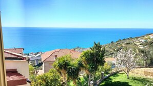 Vista costera con mar azul cristalino, casas escalonadas y abundante vegetación.