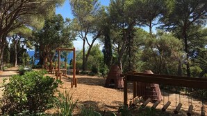 Un parque infantil con columpios, estructuras para escalar y una pequeña caseta.