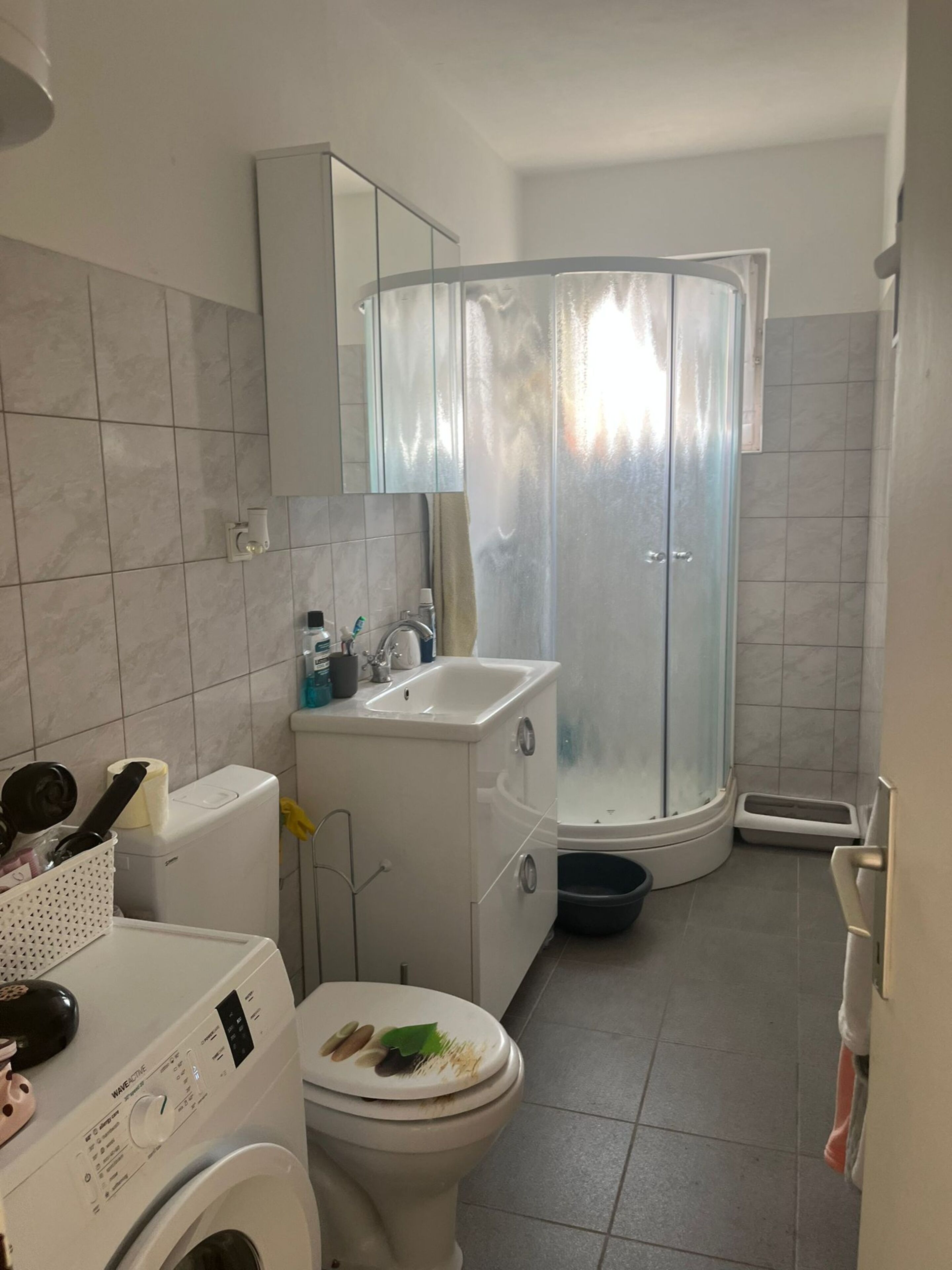 A compact bathroom with a toilet, sink, and a shower enclosure.
