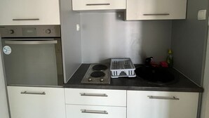 Cocina compacta con estufa, horno y pileta.