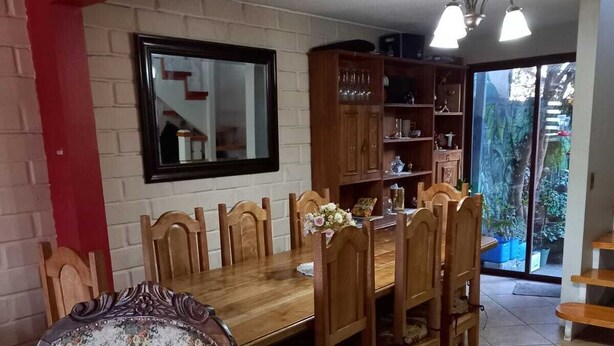 Un comedor con una mesa y sillas de madera, una pared de acento roja y vistas al exterior.