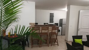A modern kitchen with a central island, wooden chairs, a washing machine, and a refrigerator. - Les Deux Mers residence on R+1 level, 150 m from the beach. (Les Trois Ilets)
