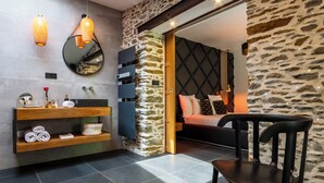 A modern bathroom with a stone accent wall, a wooden vanity, and a mirror.