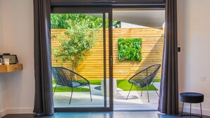 A modern bathroom with a large bathtub, a glass door leading to an outdoor patio, and a small table with a chair.