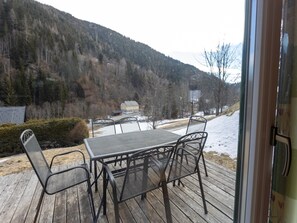 Enjoy a serene view of the forested hillside from this outdoor deck, featuring a table and chairs.