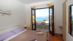 A bedroom with a bed, a nightstand, and a view of the outside balcony. - Apartments Dubreta - Superior Two Bedroom Apartment With Balcony (Konavle)