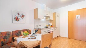 Une cuisine compacte avec des meubles blancs, une table à manger avec des chaises et un petit coin salon avec un canapé.