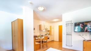 Une chambre d’hôtel comprenant un lit, une télévision, une kitchenette et un coin repas.