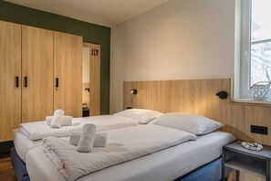 A hotel room with two beds, wooden wardrobes, a bedside table with a lamp, and a window with a view. - Beautiful Apartment in Viehhofen With hot tub (Viehhofen)
