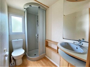 Ein kleines Badezimmer mit Dusche, Toilette und Waschbecken.