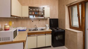 Cocina pequeña equipada con microondas, pileta, cocina y alacenas.