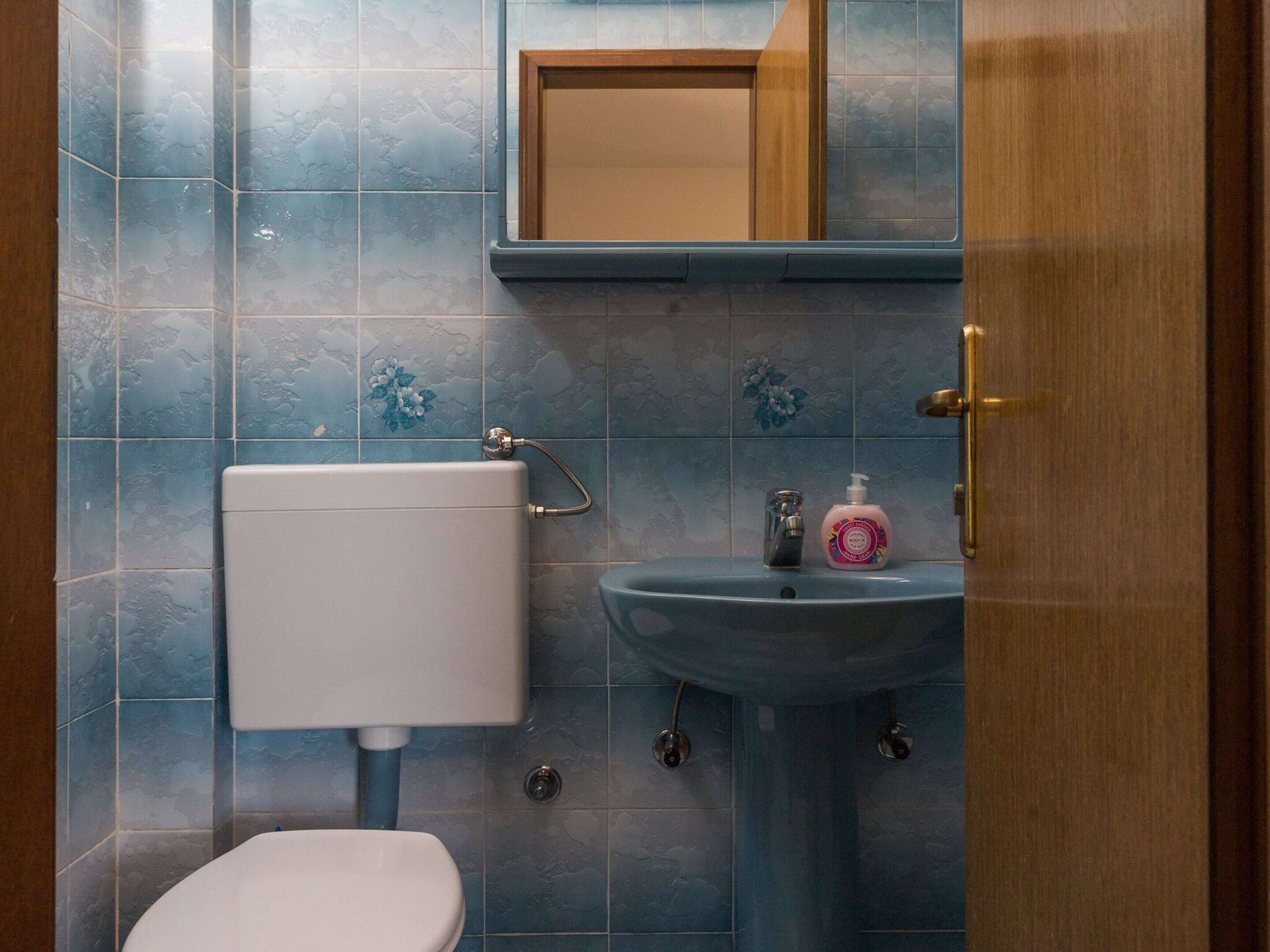 Een badkamer met toilet, wastafel en spiegel.