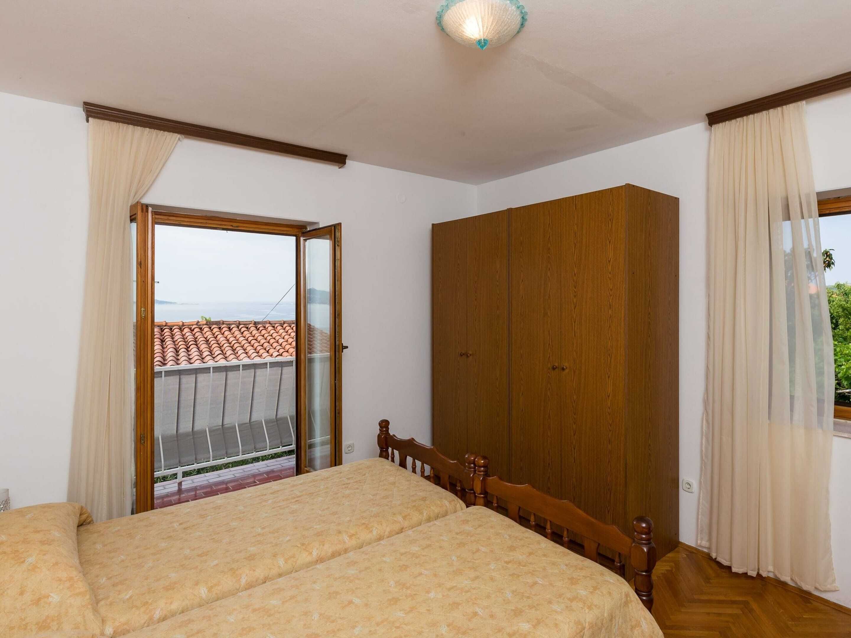 A bedroom with a bed, a wardrobe, and a balcony with a view.