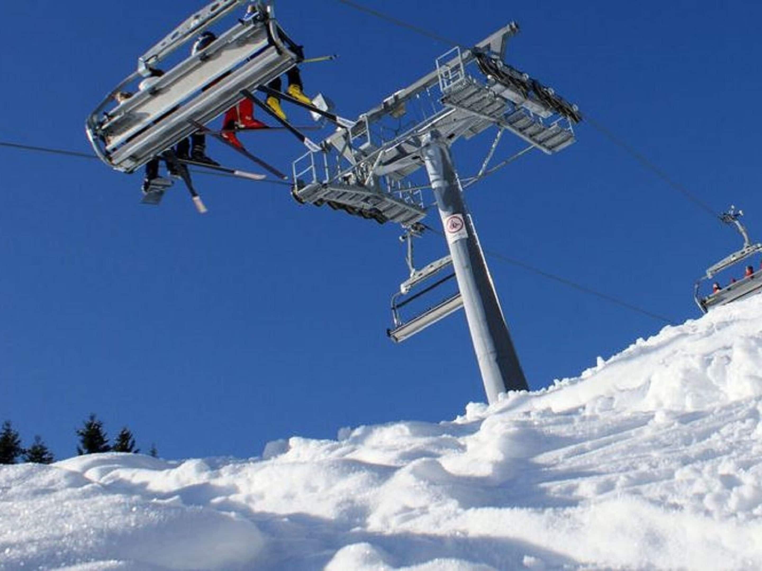 Un télésiège avec des sièges et des câbles, sur fond de ciel bleu dégagé.