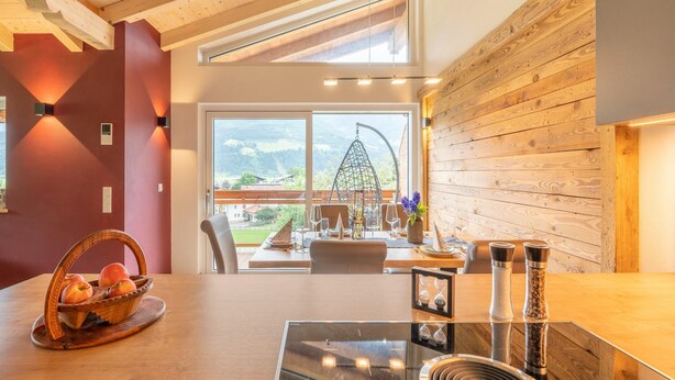 Een moderne keuken met een groot raam, houten balken in het plafond en uitzicht op de omgeving.