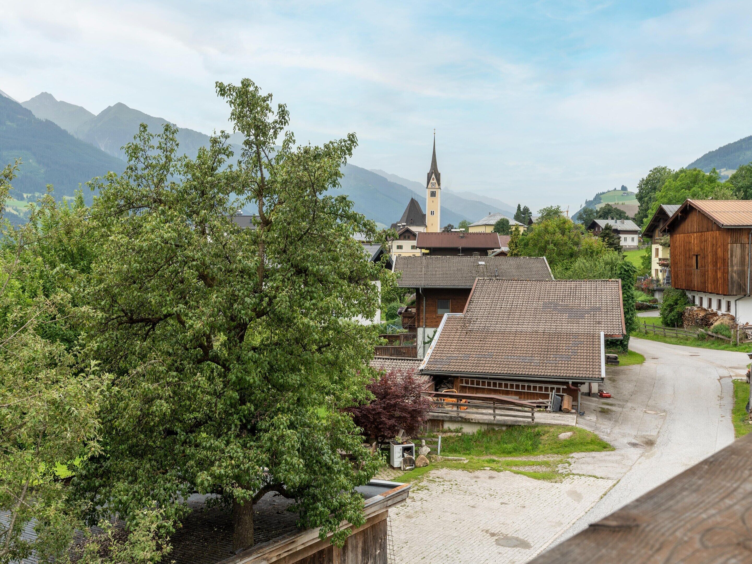 A rural village with traditional houses, a church, and mountains in the background.