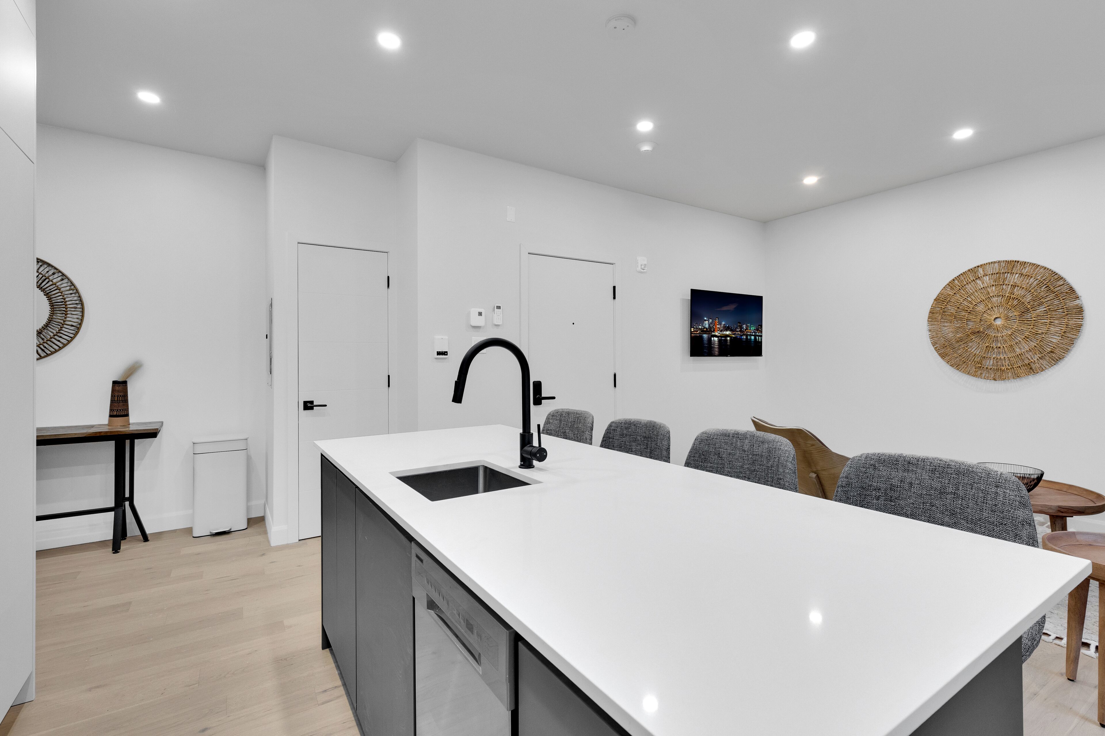 Une cuisine moderne avec un îlot central, des murs blancs et des spots encastrés au plafond.