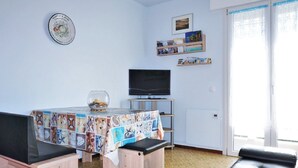 Een woonkamer met een betegelde vloer, een tafel met een foto collage, een televisie en een bank.