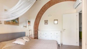 Ein Schlafzimmer mit einem Bett, einer weißen Kommode, einer weißen Klimaanlage und einer Tür zu einem anderen Raum.