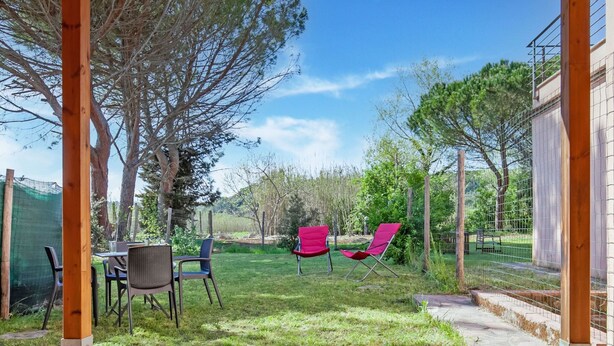 Eine Terrasse mit einer Steinmauer, zwei roten Stühlen und einem Tisch.