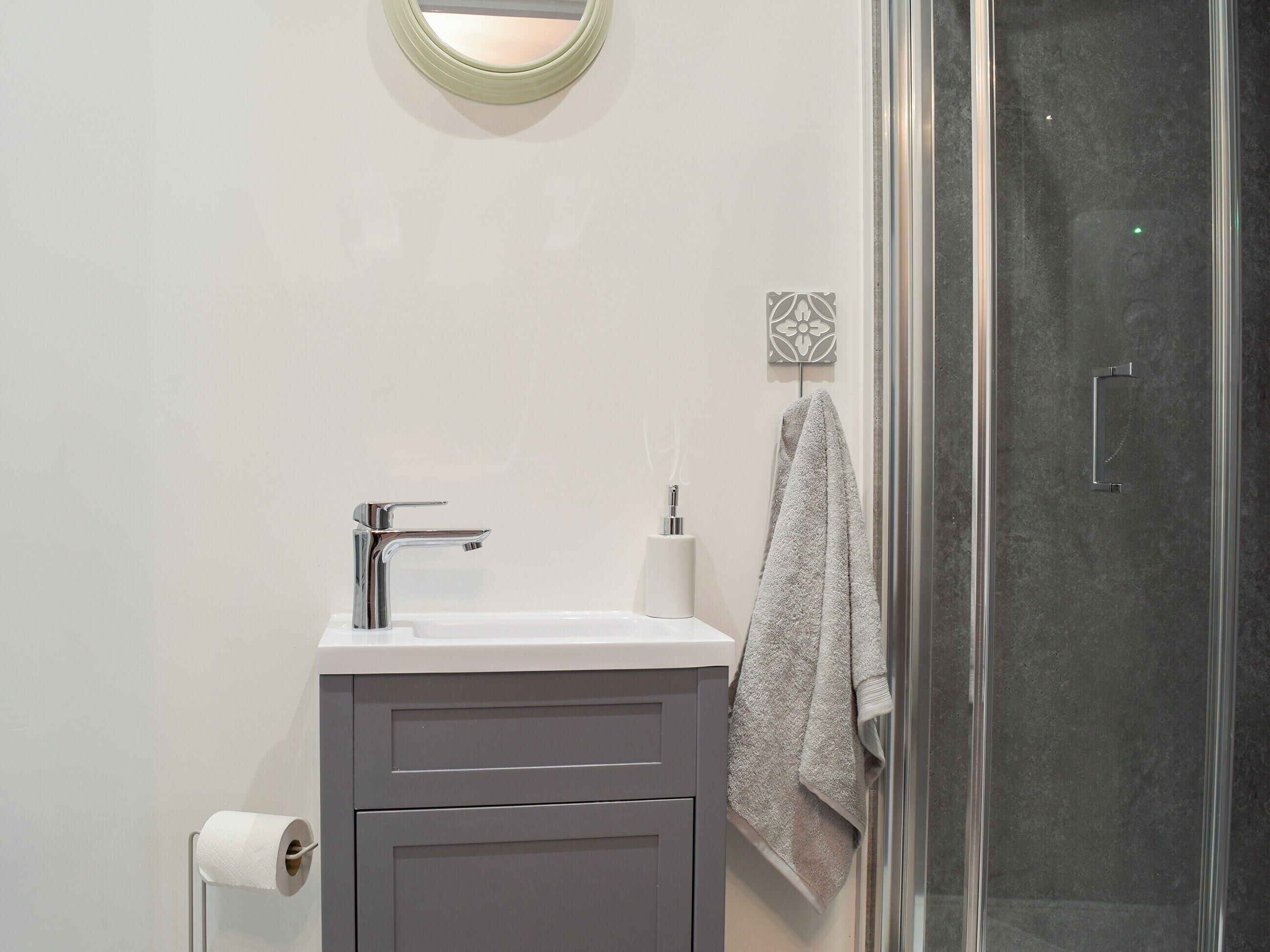 A bathroom with a modern sink, a glass shower enclosure, and a towel hanging on the wall.
