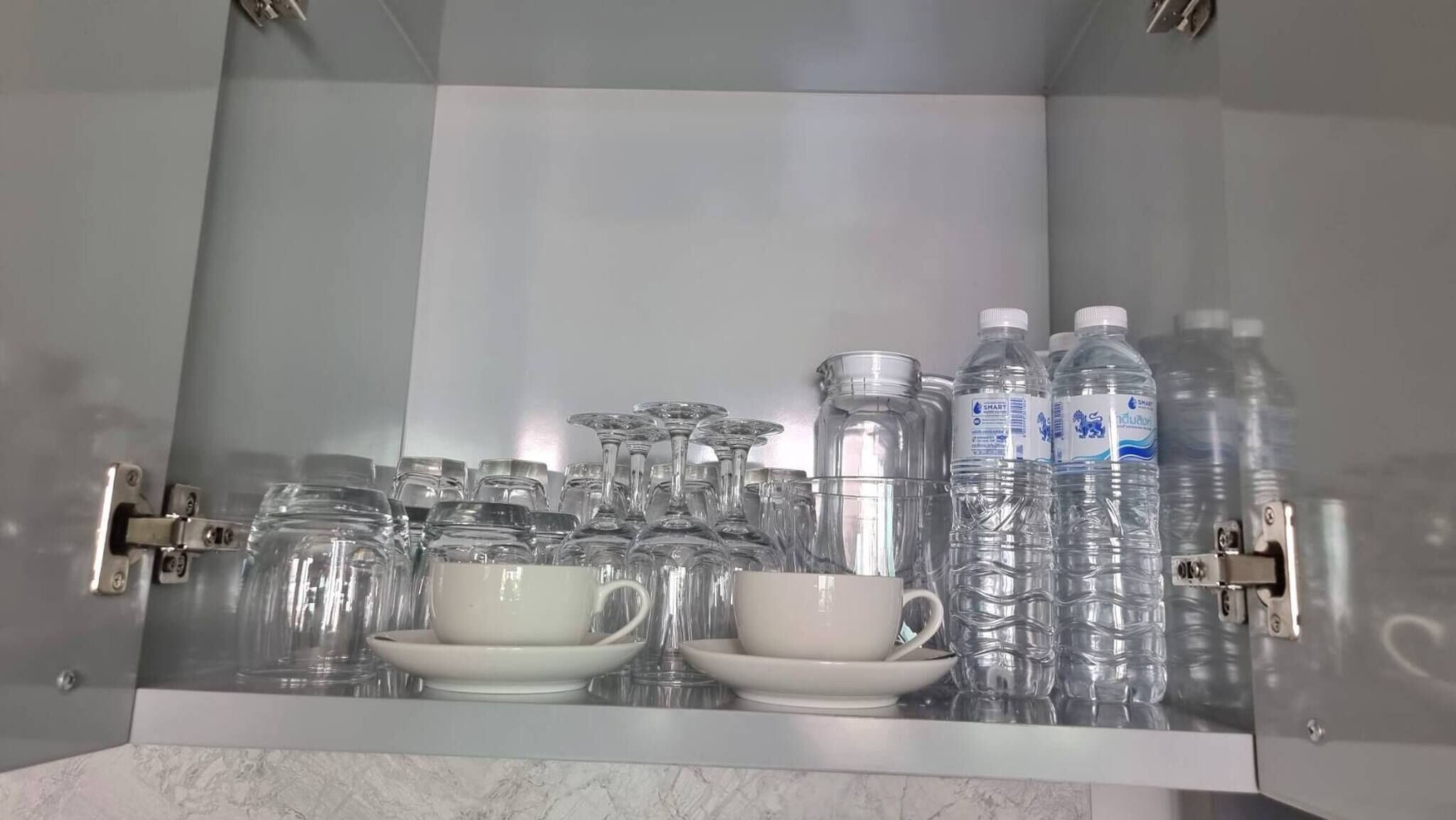 A cabinet with various glassware and water bottles.