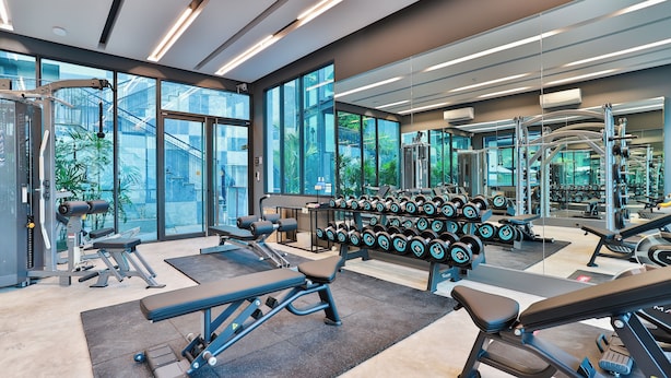 A modern gym with various exercise equipment, large windows, and a mirrored wall. - Bo501 - 2 Bdr Condo With Sea View, Ao Nang Beach (Krabi)