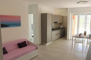 Un appartement moderne doté d’une kitchenette, d’un coin repas et d’un espace de vie avec un canapé rose.