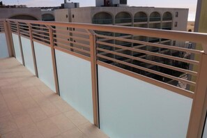 A balcony with a metal railing, a tiled floor, and a view of a building with multiple windows. - Relax Just 50mt From the Beach-beahost (San Michele al Tagliamento)