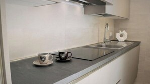 Una cocina moderna con un lavamanos de acero inoxidable, una taza sobre la encimera y una toalla blanca.