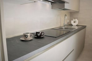 Ett modernt kök med en diskho i rostfritt stål, en enkel kaffekopp och en hjärtformad mugg på bänkskivan.