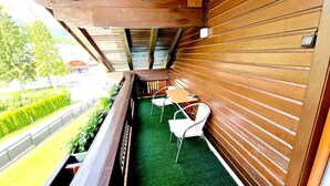A balcony with a wooden railing, a small table, and two white chairs. - Apartment Near the Gondelbahn With Shared Pool (Hermagor-Pressegger See)