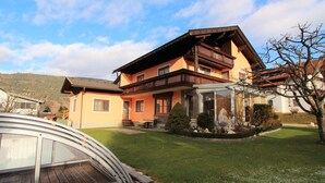 A two-story house with a balcony, a covered patio, and a well-maintained lawn. - Apartment Near the Gondelbahn With Shared Pool (Hermagor-Pressegger See)