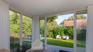 A modern room with large sliding glass doors leading to a garden. - House in Oostkapelle Near Beach & Sauna (Oostkapelle)