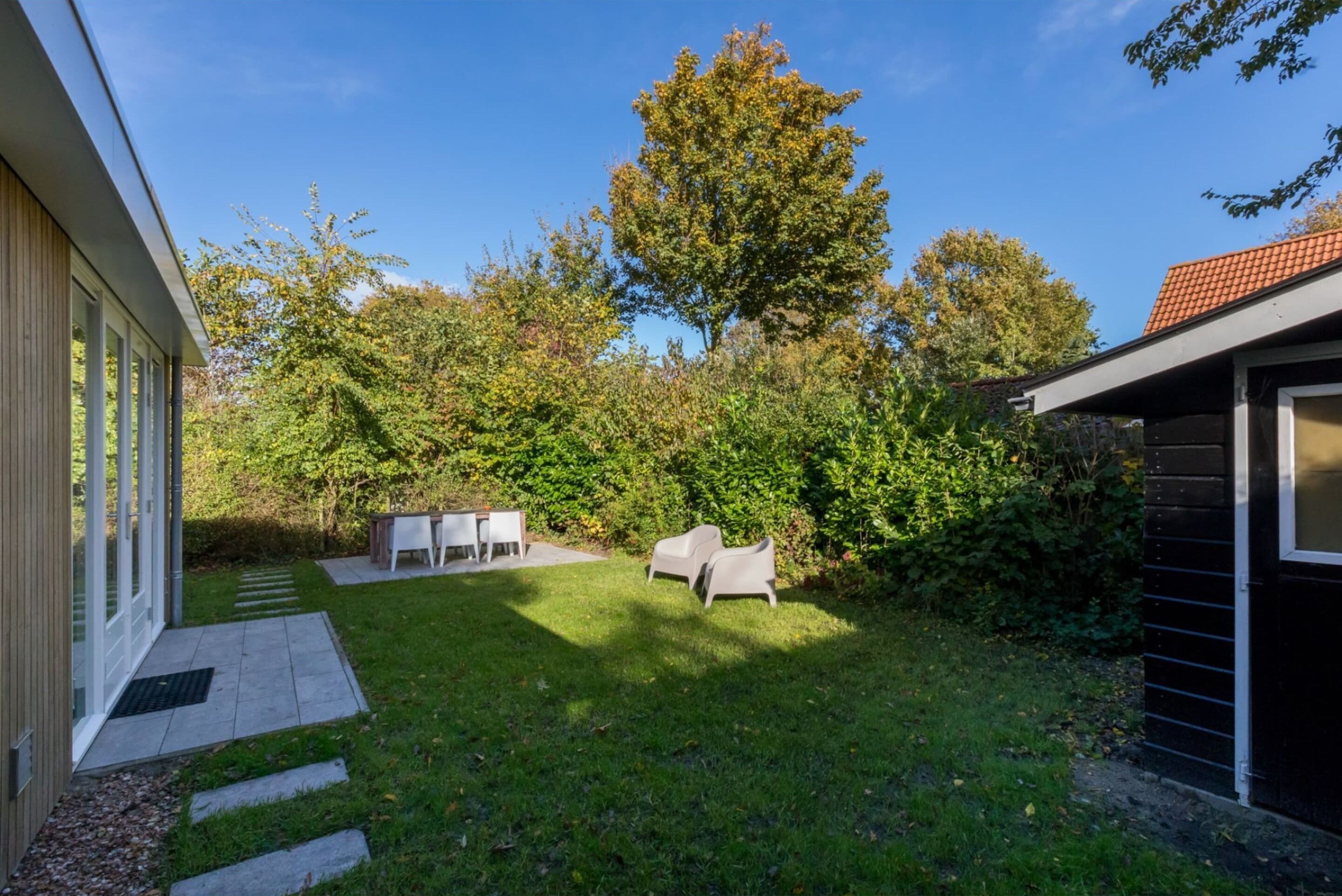 Une maison moderne dotée d’un patio, d’une table à manger et de deux chaises.